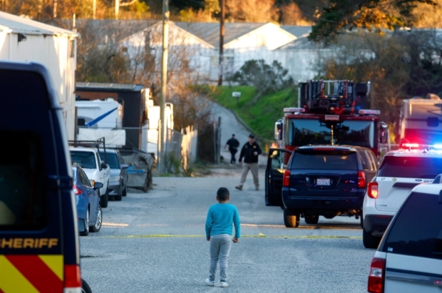 A child keeps an eye on law enforcement officers as they investigate a shooting off of Highway 92 in Half Moon Bay, Calif., on Monday, Jan. 23, 2023. (Nhat V. Meyer/Bay Area News Group)